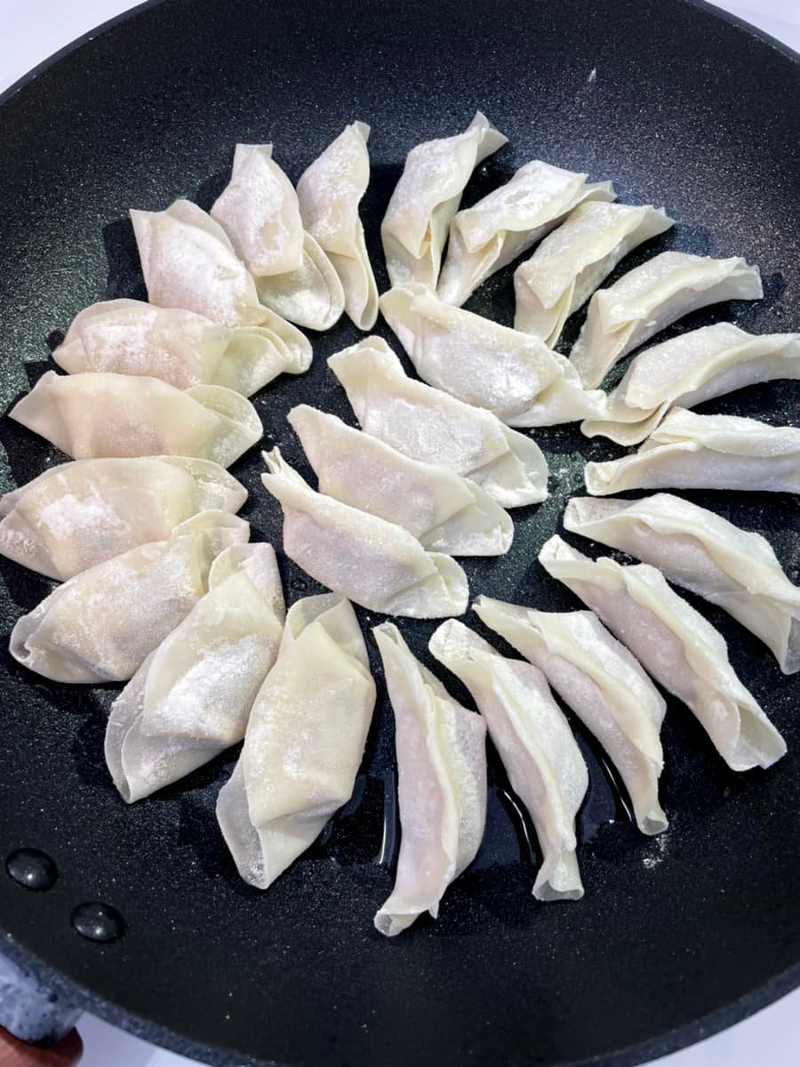 鉄なべに並ぶ仕込み前の餃子